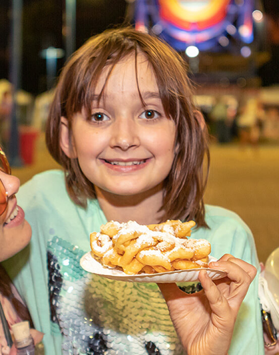 Girl holding a large funnel cake at the Red River Revel.